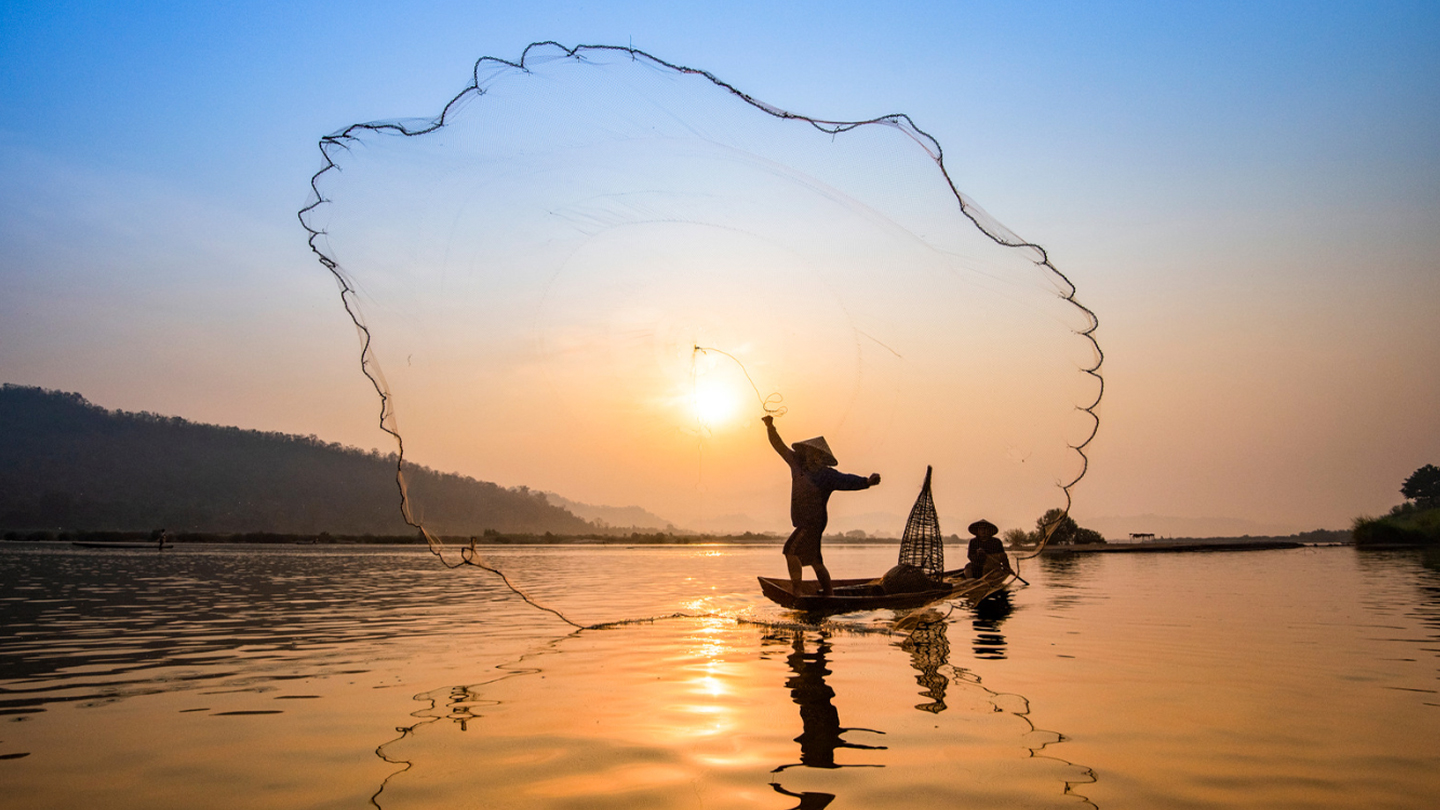 Un pêcheur lance son filet au lever du soleil au Vietnam